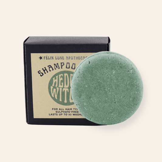 A round green shampoo bar set in front of a black box and kraft label.