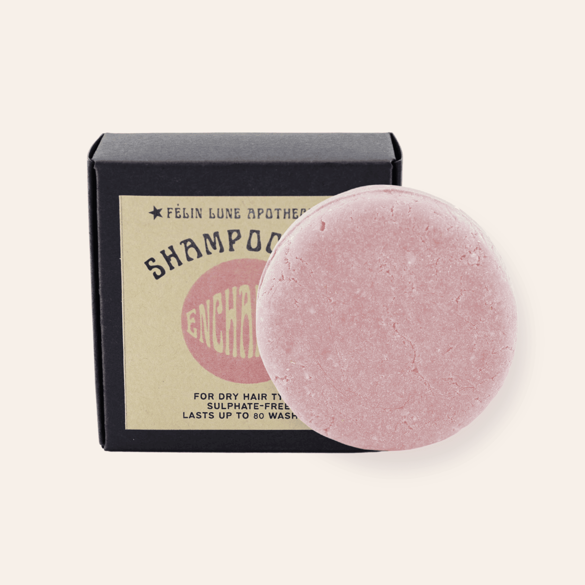 A round pink shampoo bar set in front of a black box and kraft label.
