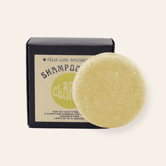 A round yellow shampoo bar set in front of a black box and kraft label.