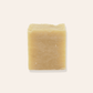 A bar of yellow natural coconut milk soap on a cream background.